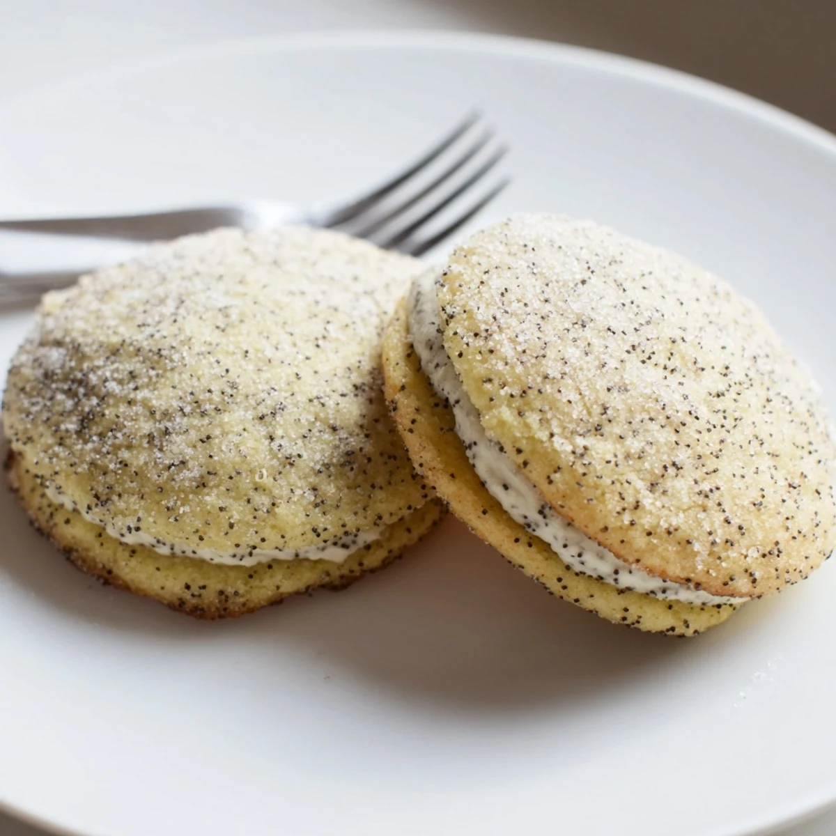 Golden lemon poppy seed cheesecake cookies with creamy centers and sugar coating on white plate