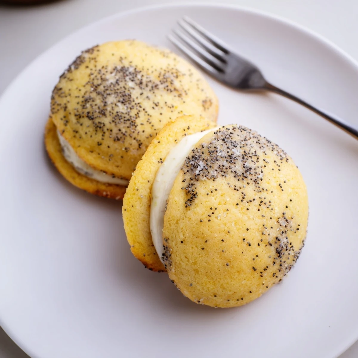 Freshly baked lemon poppy seed cheesecake cookies oozing tangy cream cheese filling on wire rack