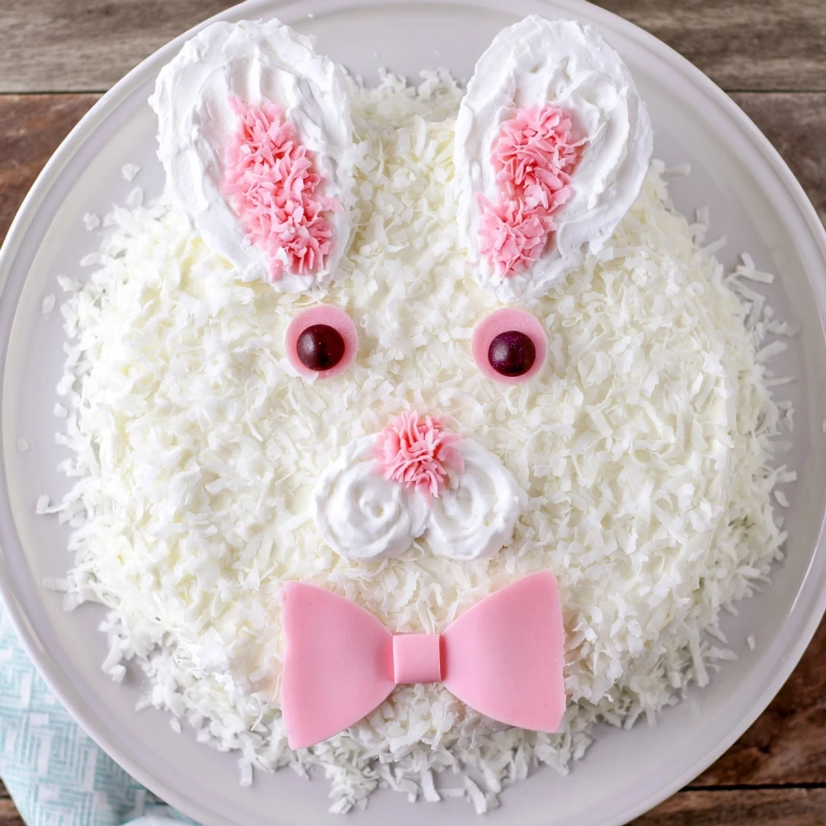 Adorable white bunny cake covered in fluffy coconut with pink candy details