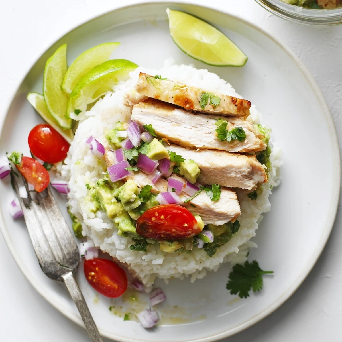 Vibrant honey lime chicken avocado rice stack served on a white plate with lime wedges