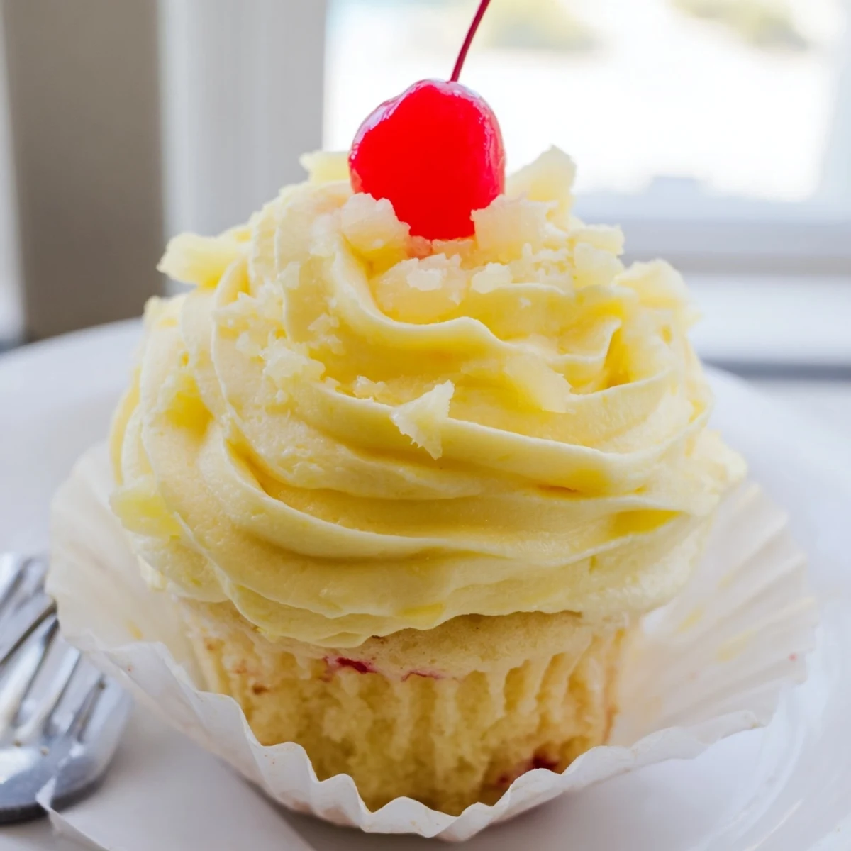 Golden Dole Whip Cupcakes topped with fluffy pineapple cream and cherry garnish