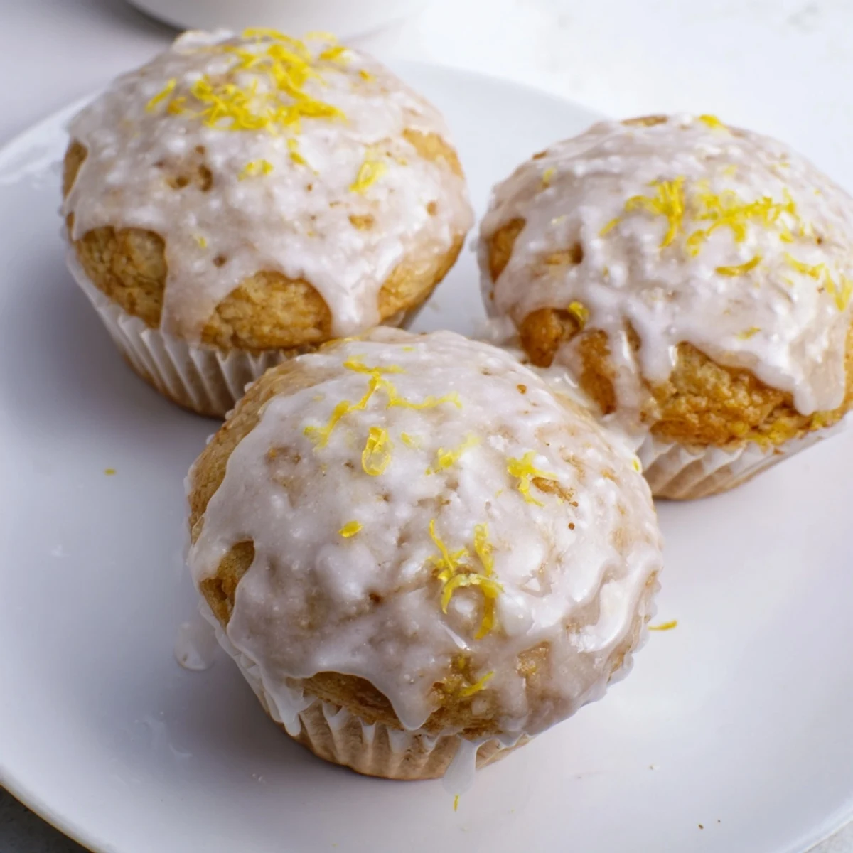 Warm Glazed Lemon Ginger Muffins topped with lemon zest, perfect for breakfast