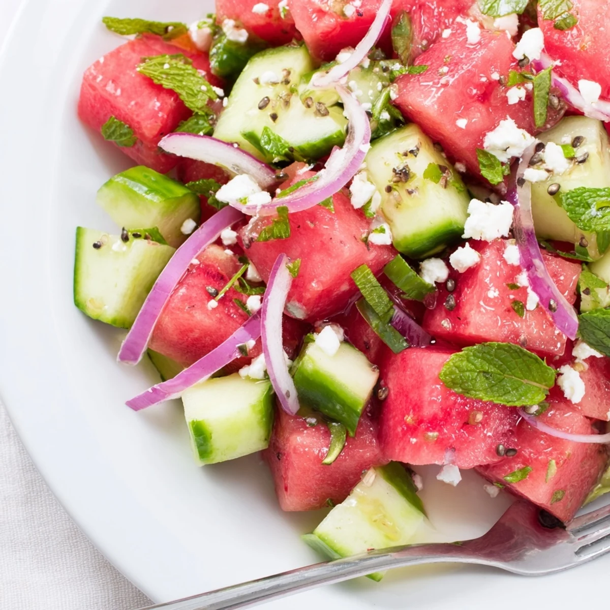 Bright Watermelon Cucumber Salad tossed in zesty lime dressing on picnic table
