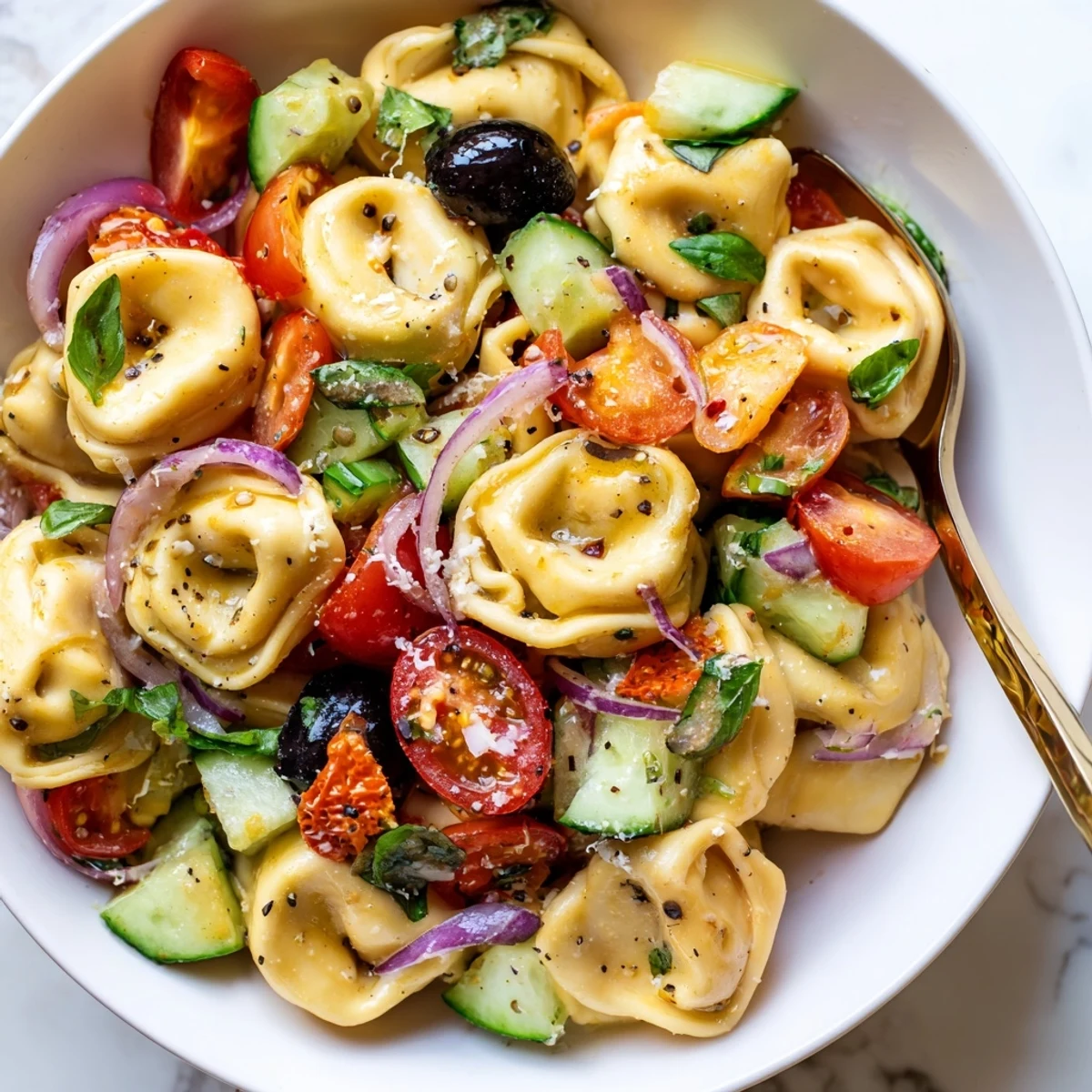Bright Tortellini Pasta Salad layered with cherry tomatoes and torn basil, chilled.