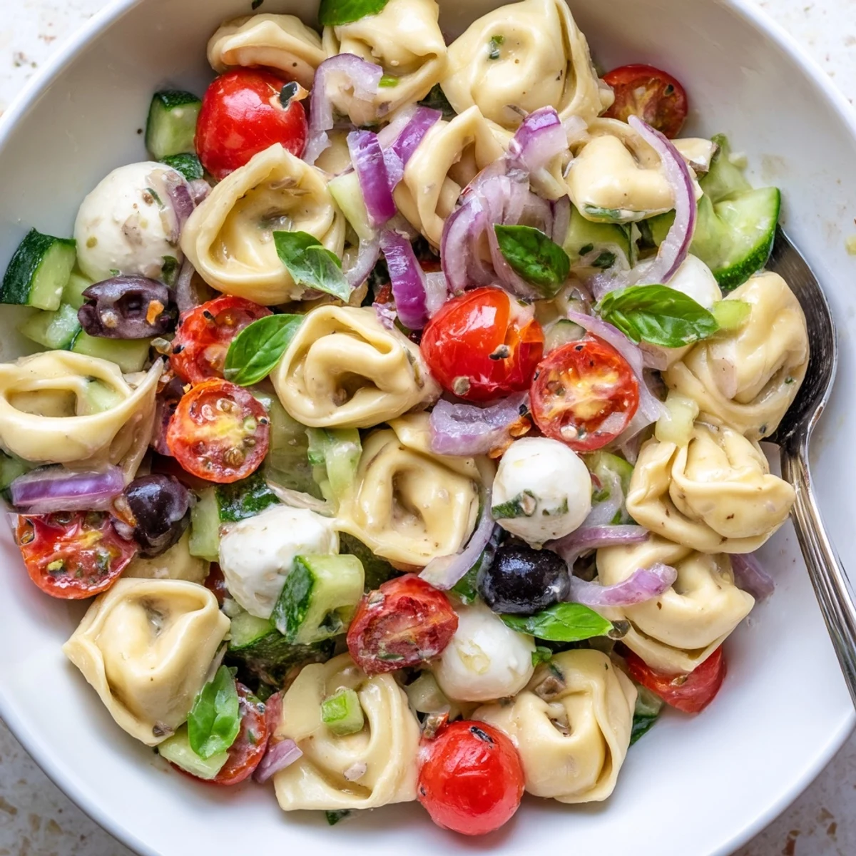 Tortellini Pasta Salad with crunchy cucumber and olives, served chilled for potlucks.