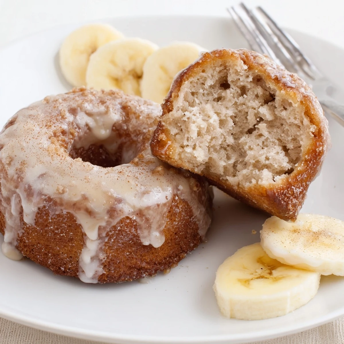 Fresh-baked Banana Donuts with golden tops, soft crumb and vanilla glaze.