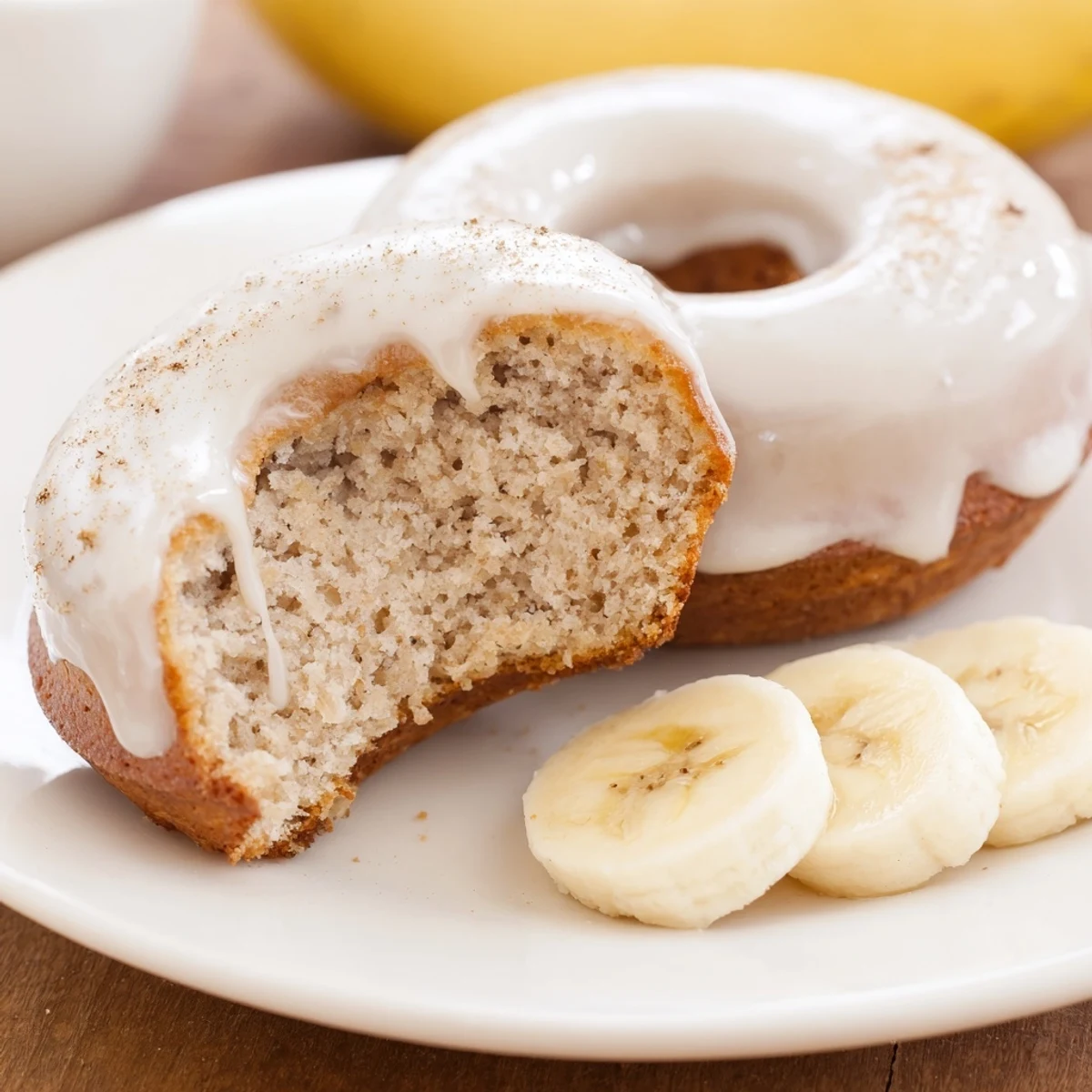 Plate of glazed Banana Donuts beside coffee, fluffy, banana aroma rising.