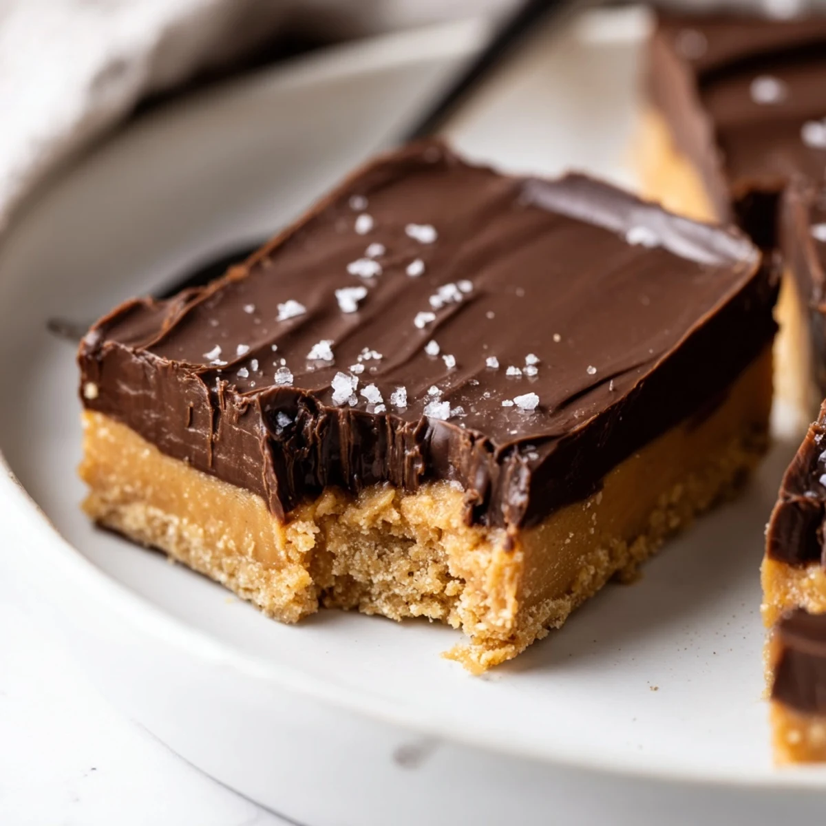 No Bake Peanut Butter Bars chilled in pan, glossy chocolate topping, cut squares