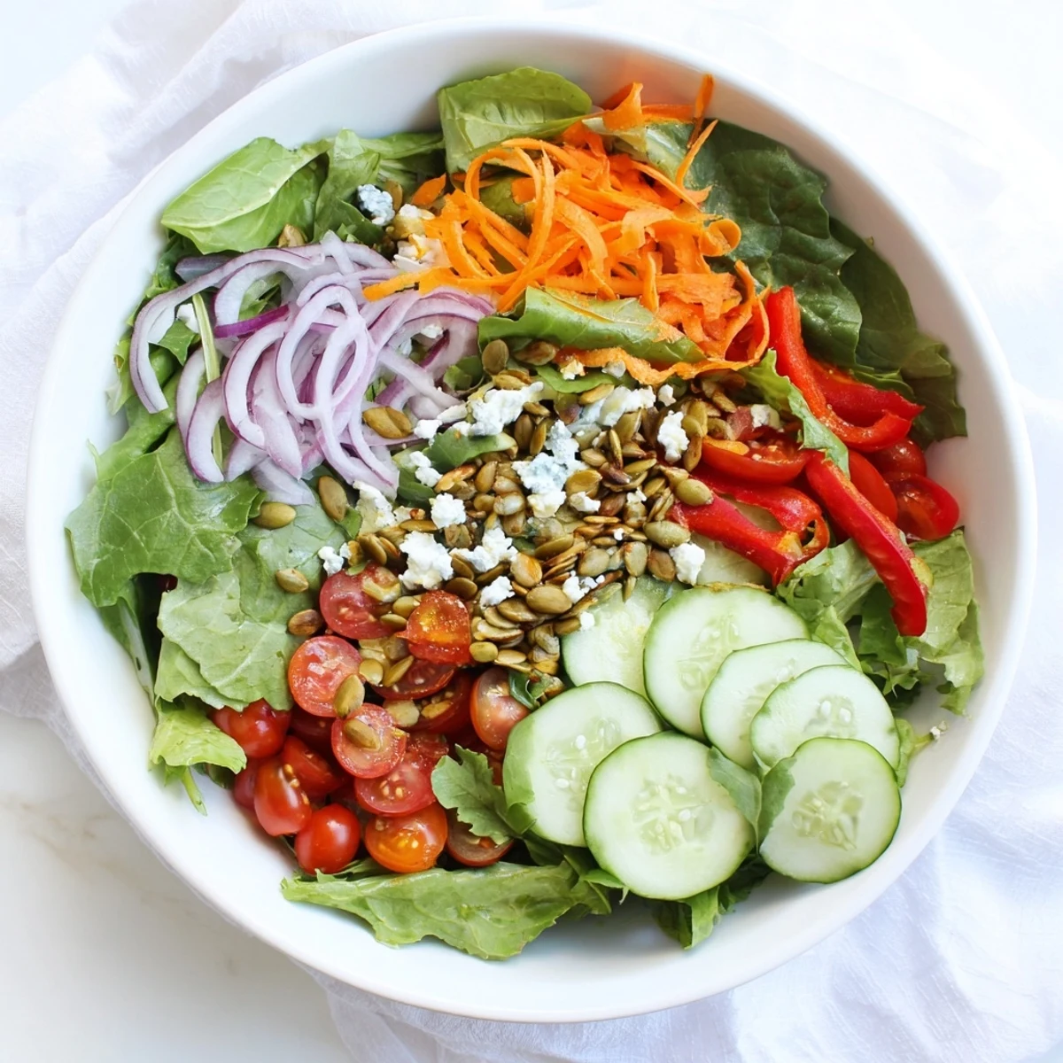 Bountiful garden salad displaying romaine, arugula, bell peppers, and shredded carrot in olive oil dressing