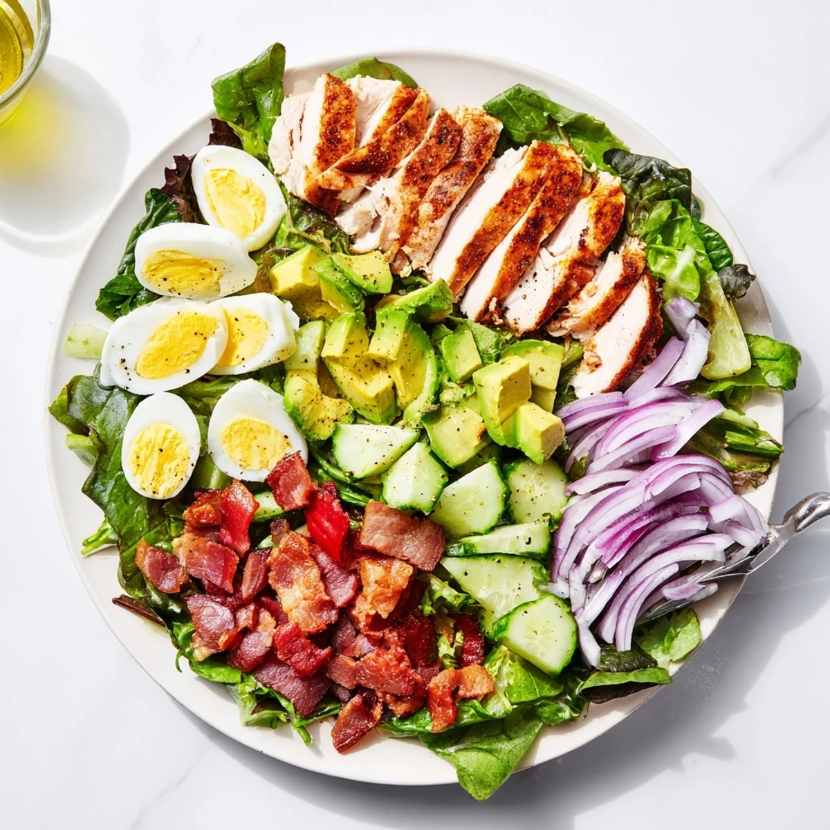 Wholesome Cobb salad platter featuring seasoned grilled chicken, crispy bacon crumbles, hard-boiled eggs, and crisp cucumber slices