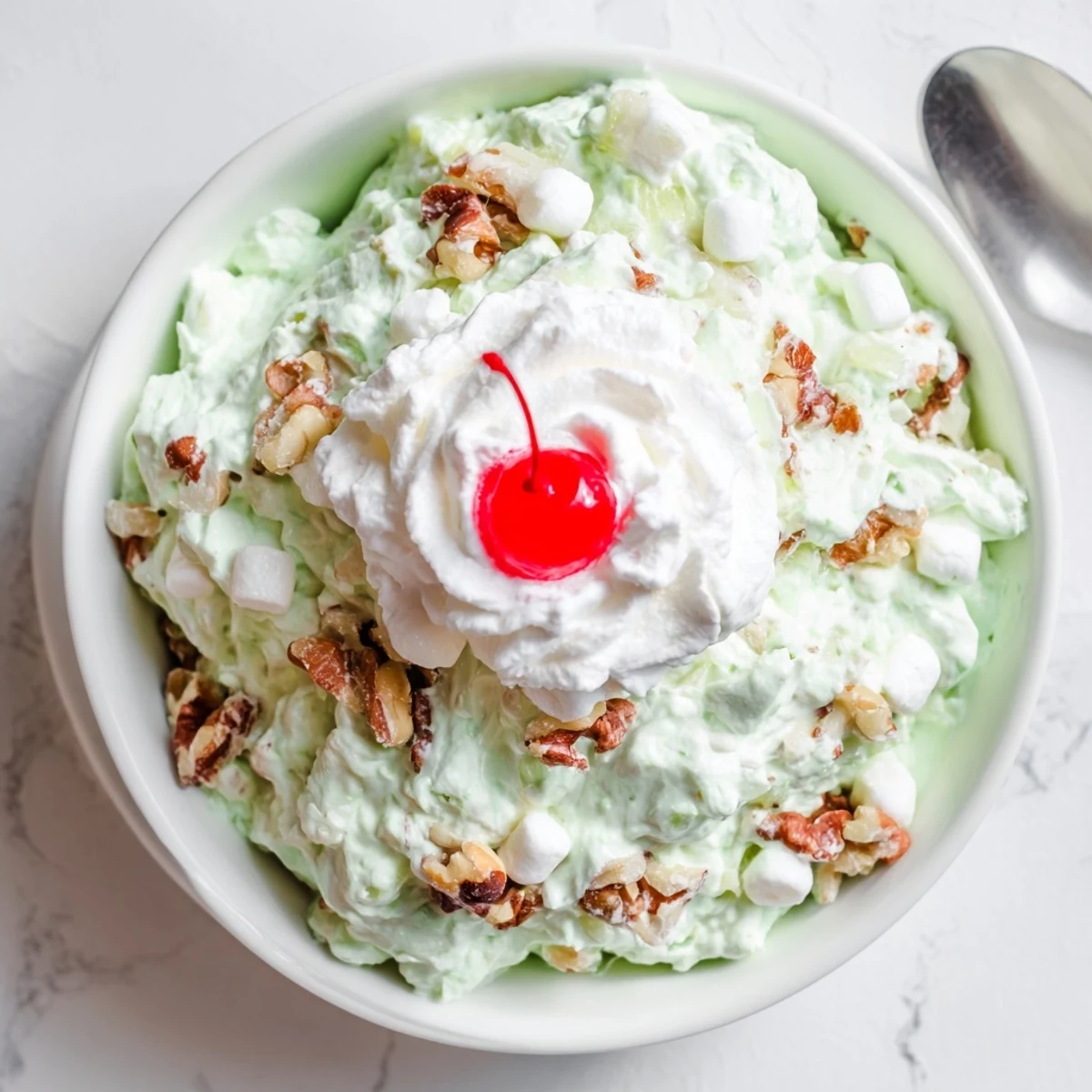 Vintage Watergate Salad topped with maraschino cherries and chopped walnuts for holiday gatherings