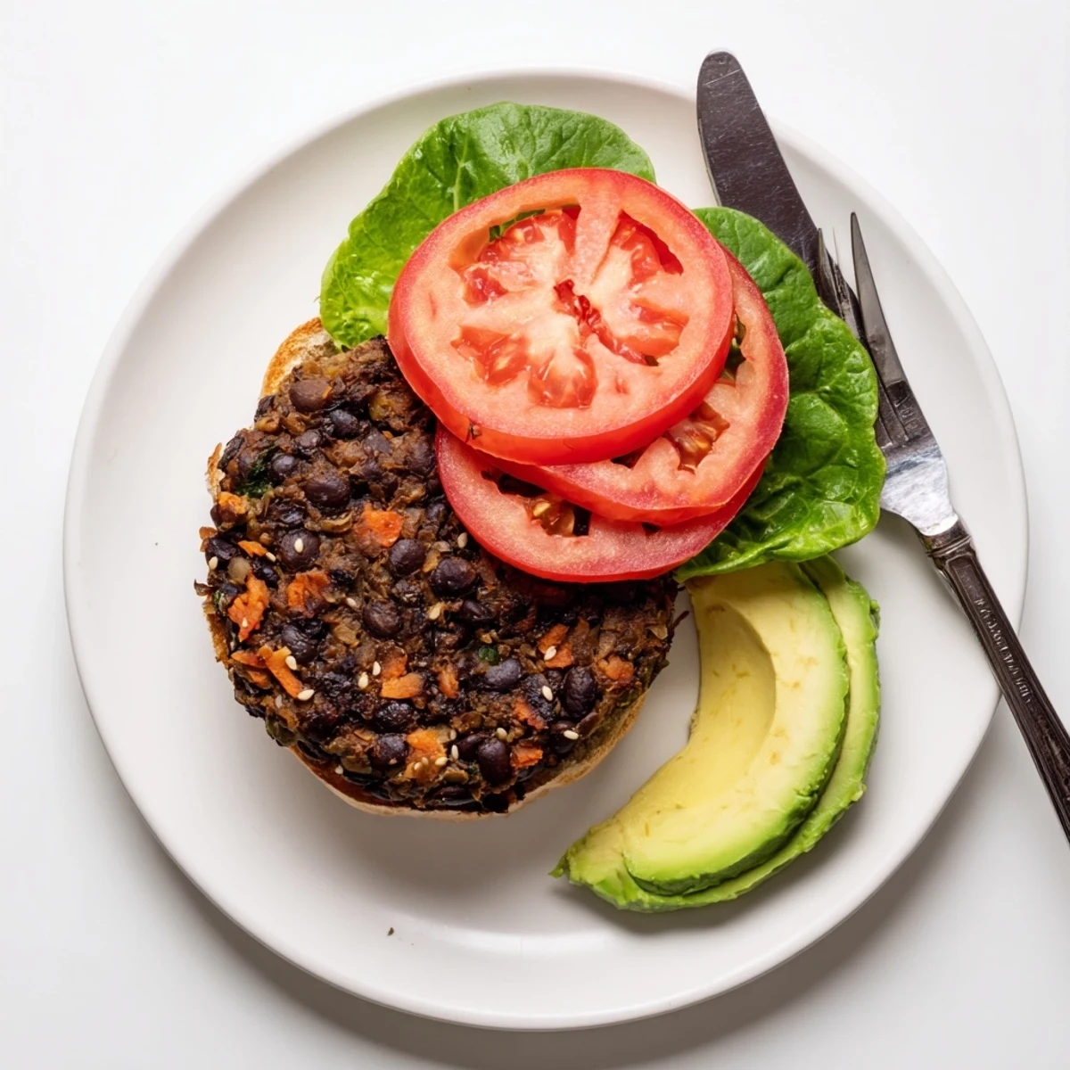 Hearty homemade veggie burger patties sizzling in a skillet with visible vegetable bits and black beans