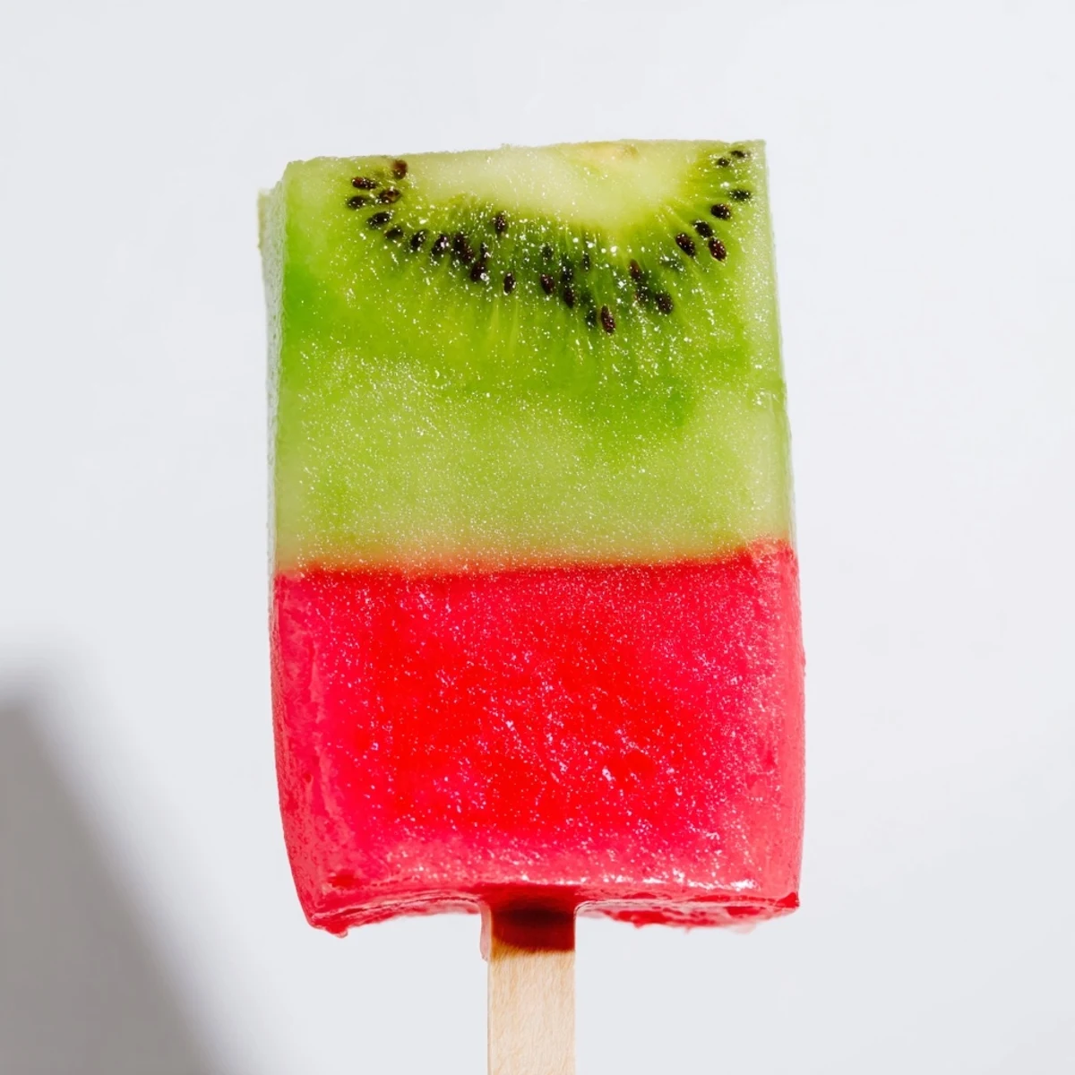 Frozen watermelon and kiwi layered popsicles displaying bright pink bottom and green top
