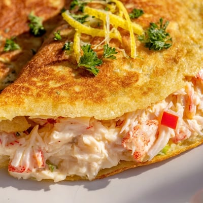 Handheld appetizer featuring shrimp and crab filling wrapped inside golden brown fried tortilla snacks