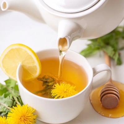 Warm earthy dandelion tea poured from glass teapot with lemon wedge on wooden board